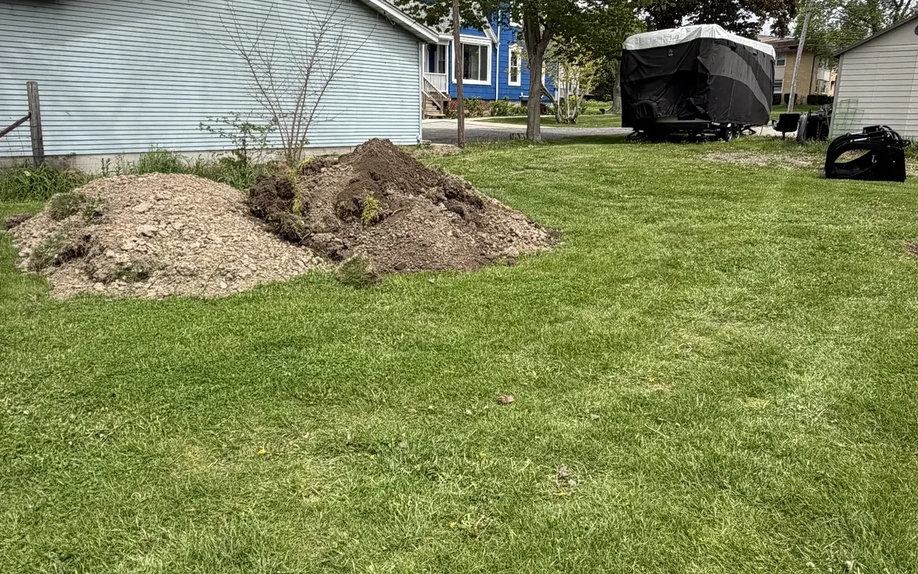 Mound of fresh stump grindings on a residential lawn after the stump was ground below grade